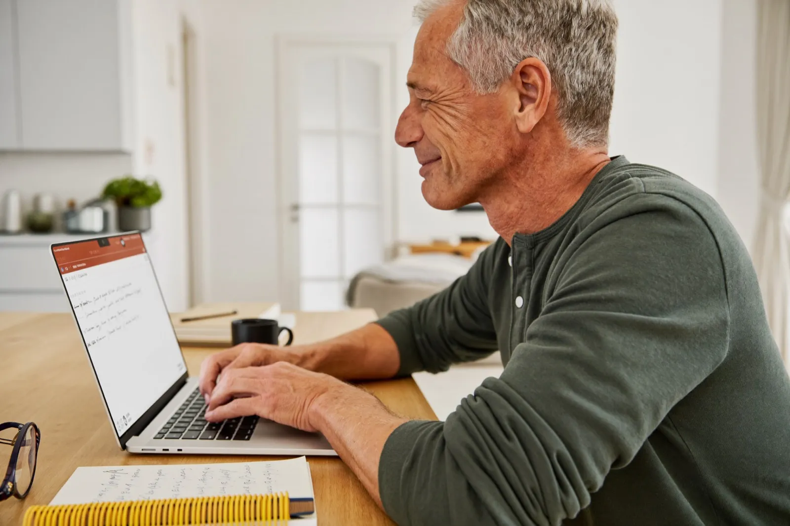 An entrepreneur in his sixties building his first own application on a laptop at the dining table